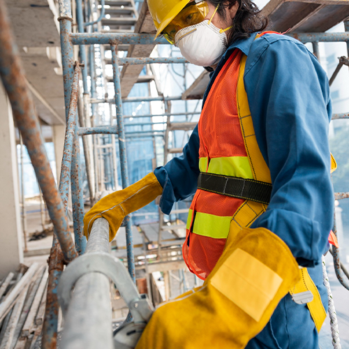 A construction worker wearing PPE beside scaffolding and site equipment